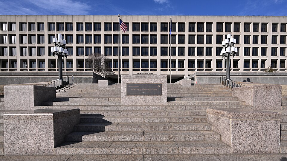 The front steps and entrance sign of the Frances Perkins Building, the US Department of Labor's headquarters on Constitution Avenue in Washington, under a blue sky