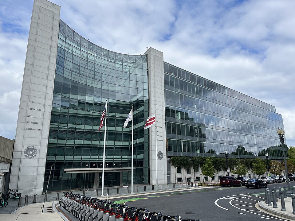 The headquarters of the U.S. Securities and Exchange Commission at 100 F Street NE in Washington: a curved glass front between two stone pillars, the left one engraved with the agency's name above its