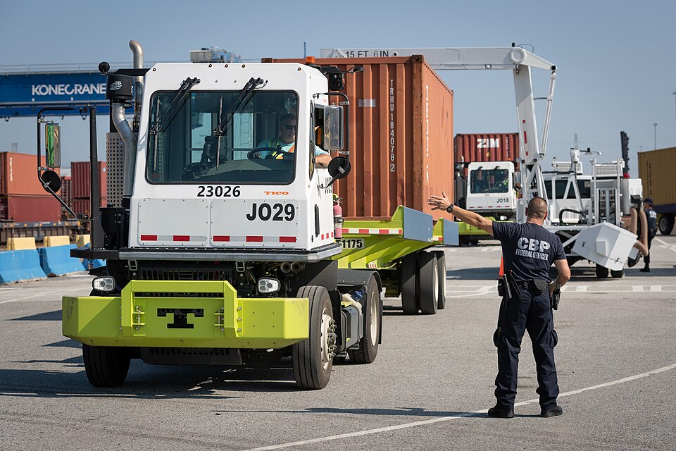 A Customs and Border Protection officer waves a yard truck carrying a shipping container through a non-intrusive inspection lane at the Port of Savannah, Georgia, in June 2023