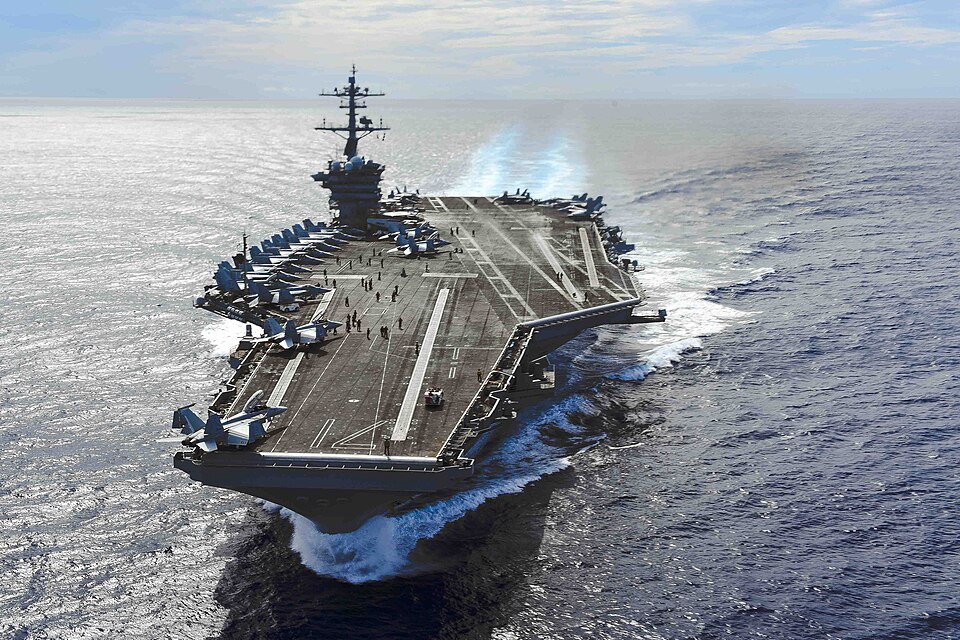 The carrier USS Theodore Roosevelt under way in the Philippine Sea on 24 September 2024, seen from the air ahead of its bow, jets parked along its flight deck