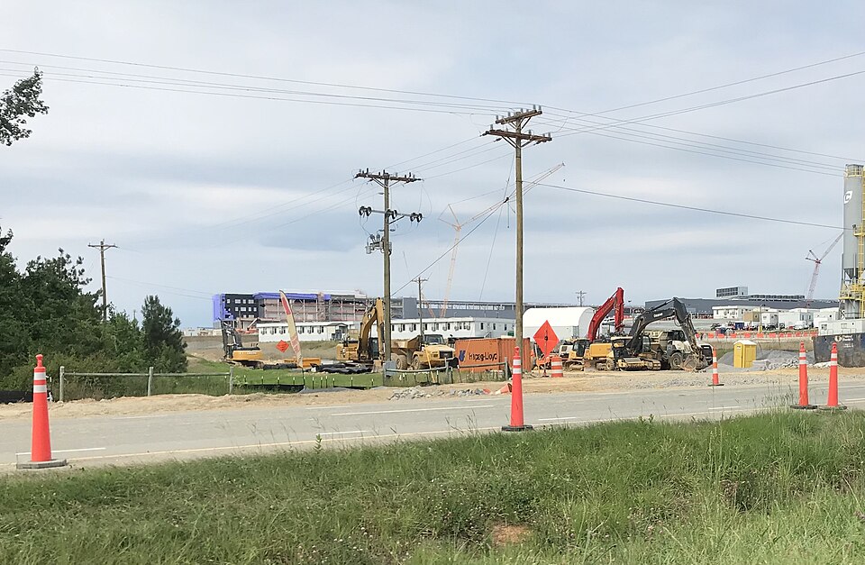 Construction machines, orange traffic cones and power lines beside a road at Wolfspeed's manufacturing site under construction in Chatham County, North Carolina, in June 2024